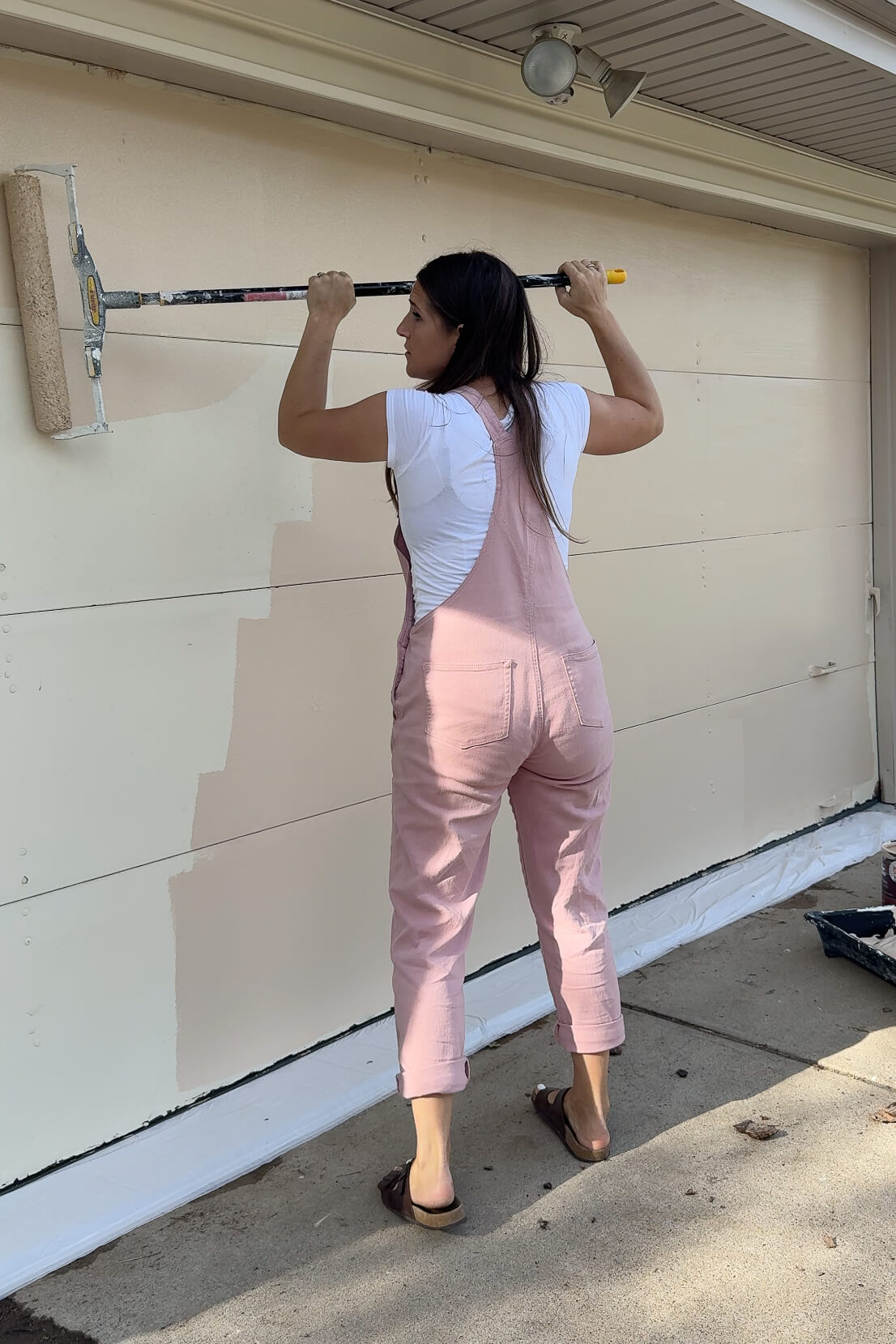 Painting a base coat on my garage door before painting it to look like faux wood grain.